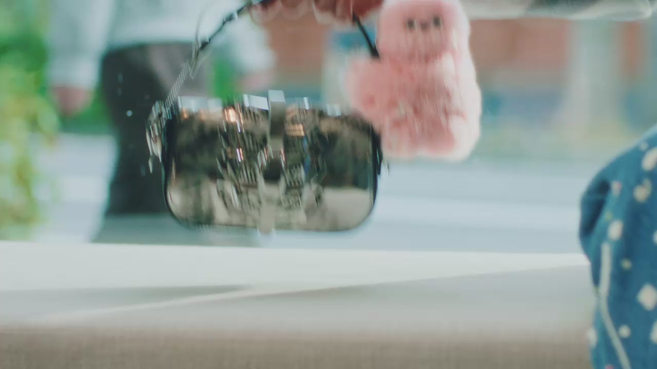 Video titled "A Day With Mirumi." A woman carrying the Mirumi bag charm robot travels through a cafe, a train, and a movie theater, showcasing its charming presence in her daily life.